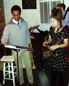 Jason Palmer holding a trumpet and reviewing sheet music next to saxophonist Grace Kelly during a performance at Wally’s Cafe Jazz Club.