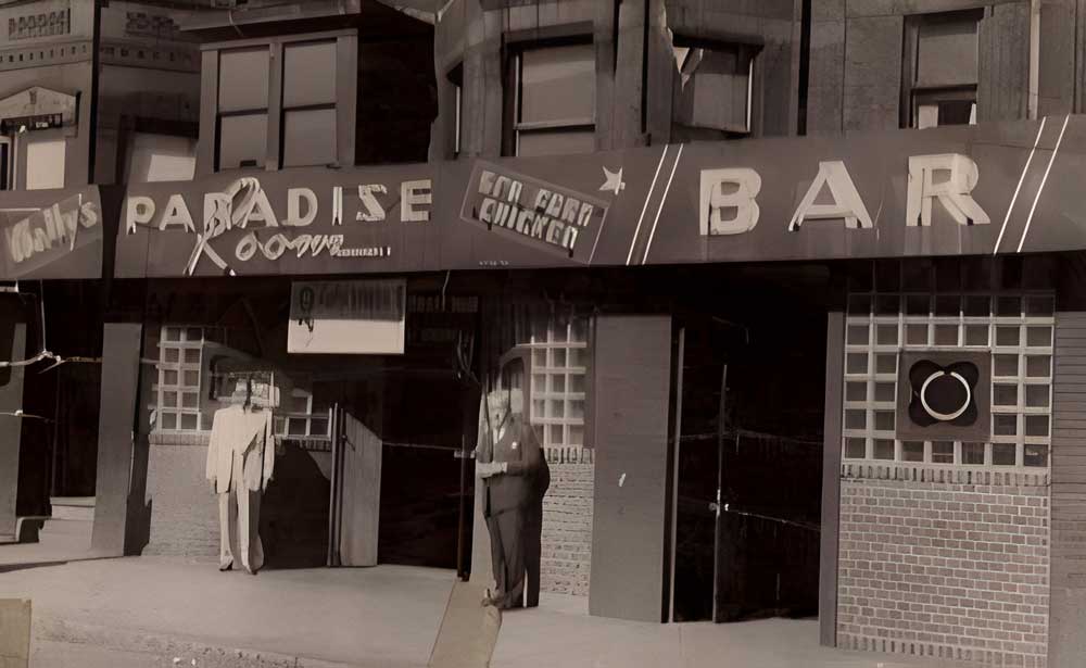 Historic black-and-white photo of Wally’s Cafe, formerly known as Wally’s Paradise, on Massachusetts Avenue in Boston’s South End, with original signage and patrons standing outside.