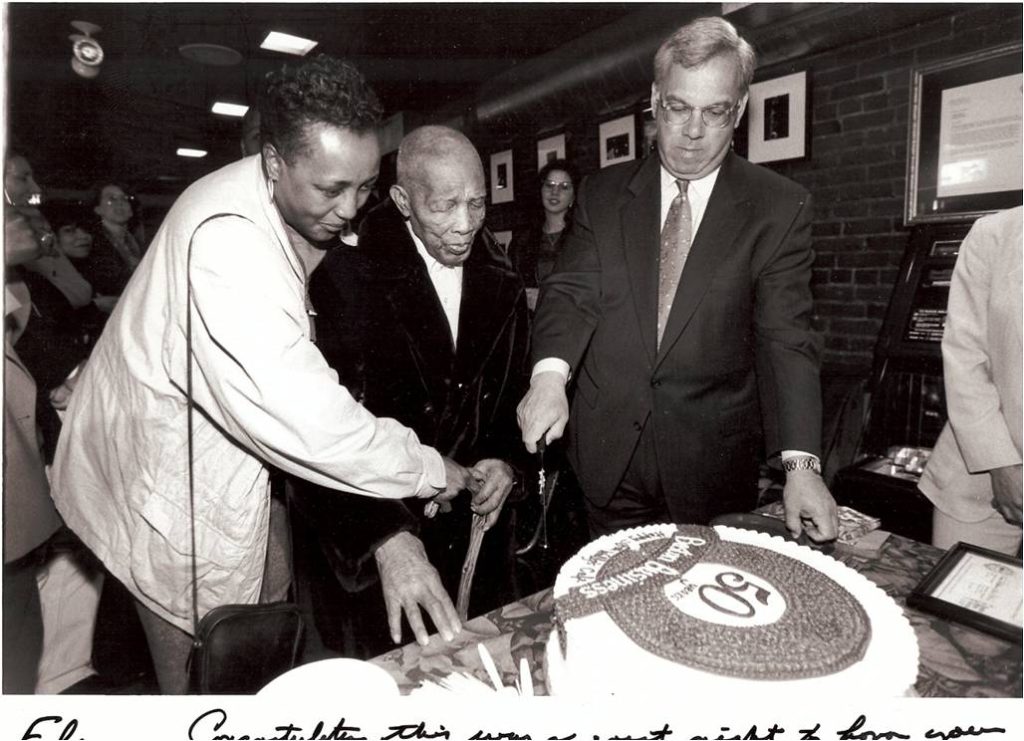 Joseph Walcott cutting a 50th anniversary cake beside Boston Mayor Thomas Menino
